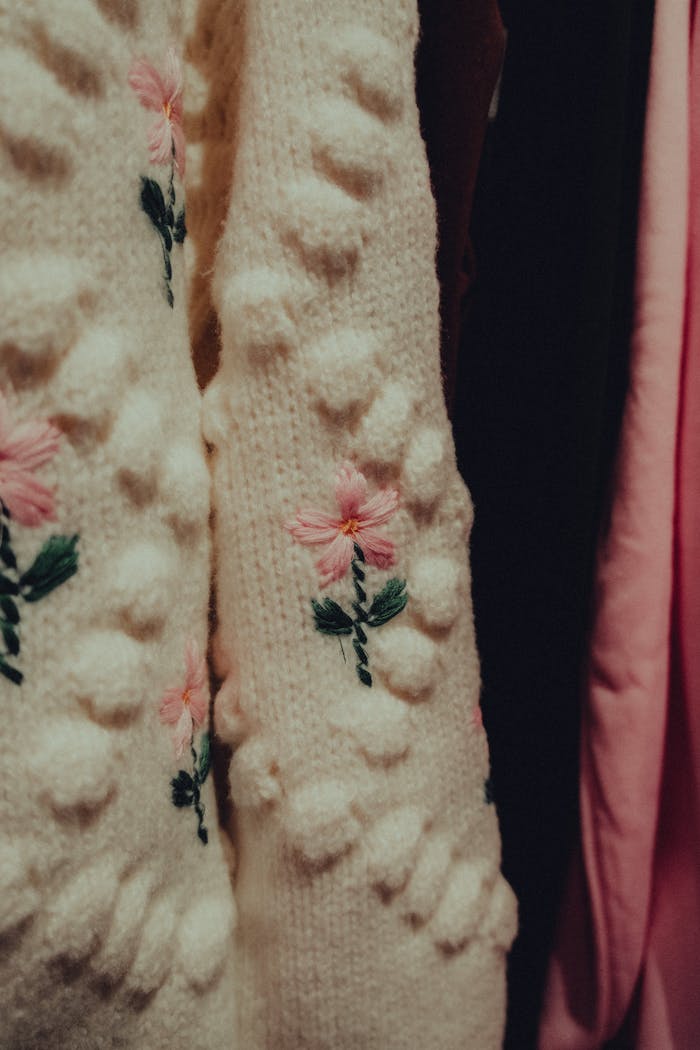 Detailed view of a handmade knitted sweater with floral embroidery, showcasing intricate craftsmanship.