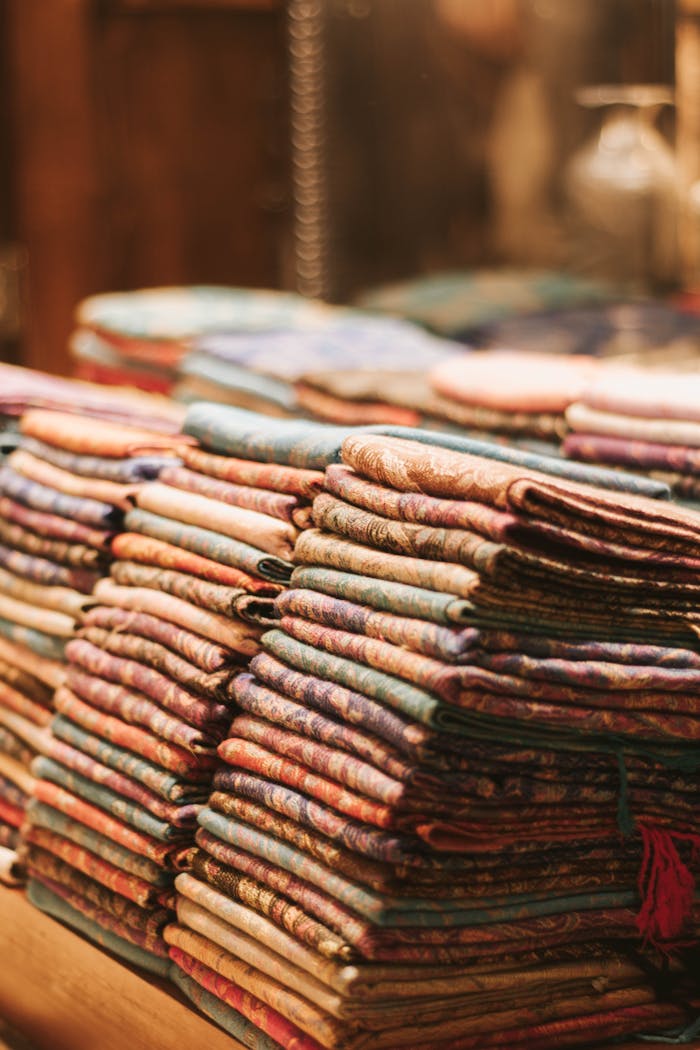 Close-up of neatly stacked colorful fabrics in a warm-lit store display, creating a cozy ambiance.
